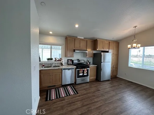 a kitchen with stainless steel appliances granite countertop a refrigerator stove a sink dishwasher and a oven with wooden floor