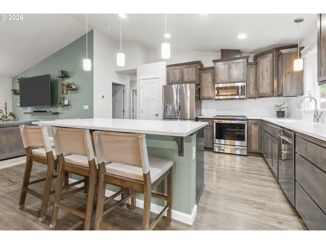 a kitchen with stainless steel appliances kitchen island granite countertop a table chairs sink and cabinets