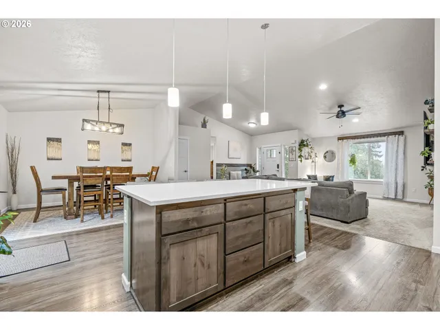 a kitchen with stainless steel appliances kitchen island granite countertop a table chairs and a refrigerator