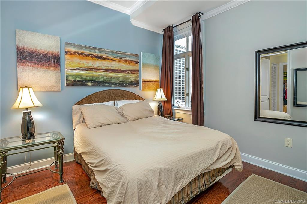 230 South Tryon Street, Unit 703 Charlotte, NC 28202 - Photo 12 of 22 a bedroom with a bed a lamp on dresser and a window