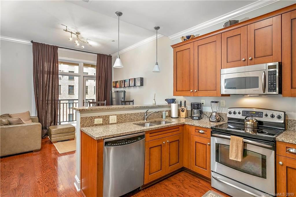 230 South Tryon Street, Unit 703 Charlotte, NC 28202 - Photo 6 of 22 a kitchen with stainless steel appliances granite countertop a stove a sink and a microwave