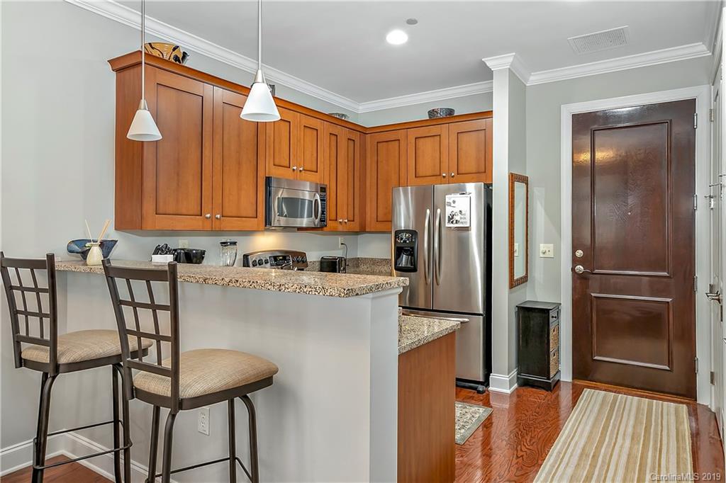 230 South Tryon Street, Unit 703 Charlotte, NC 28202 - Photo 7 of 22 a kitchen with stainless steel appliances granite countertop a refrigerator a stove and white cabinets with wooden floor