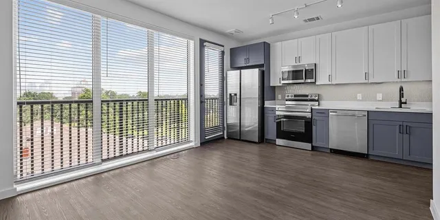 a view of a kitchen with stainless steel appliances granite countertop a stove a sink and white cabinets