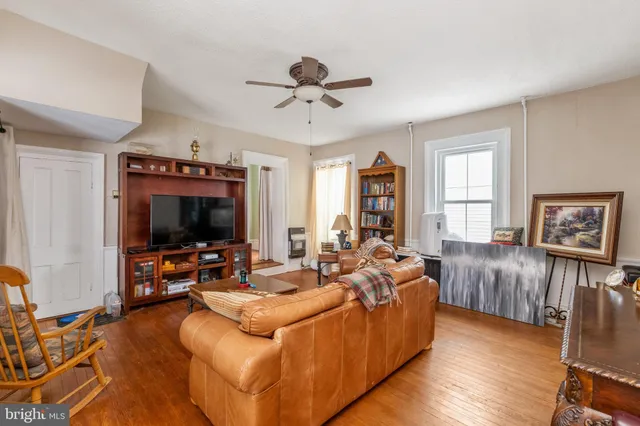 a living room with furniture ceiling fan and a wooden floor
