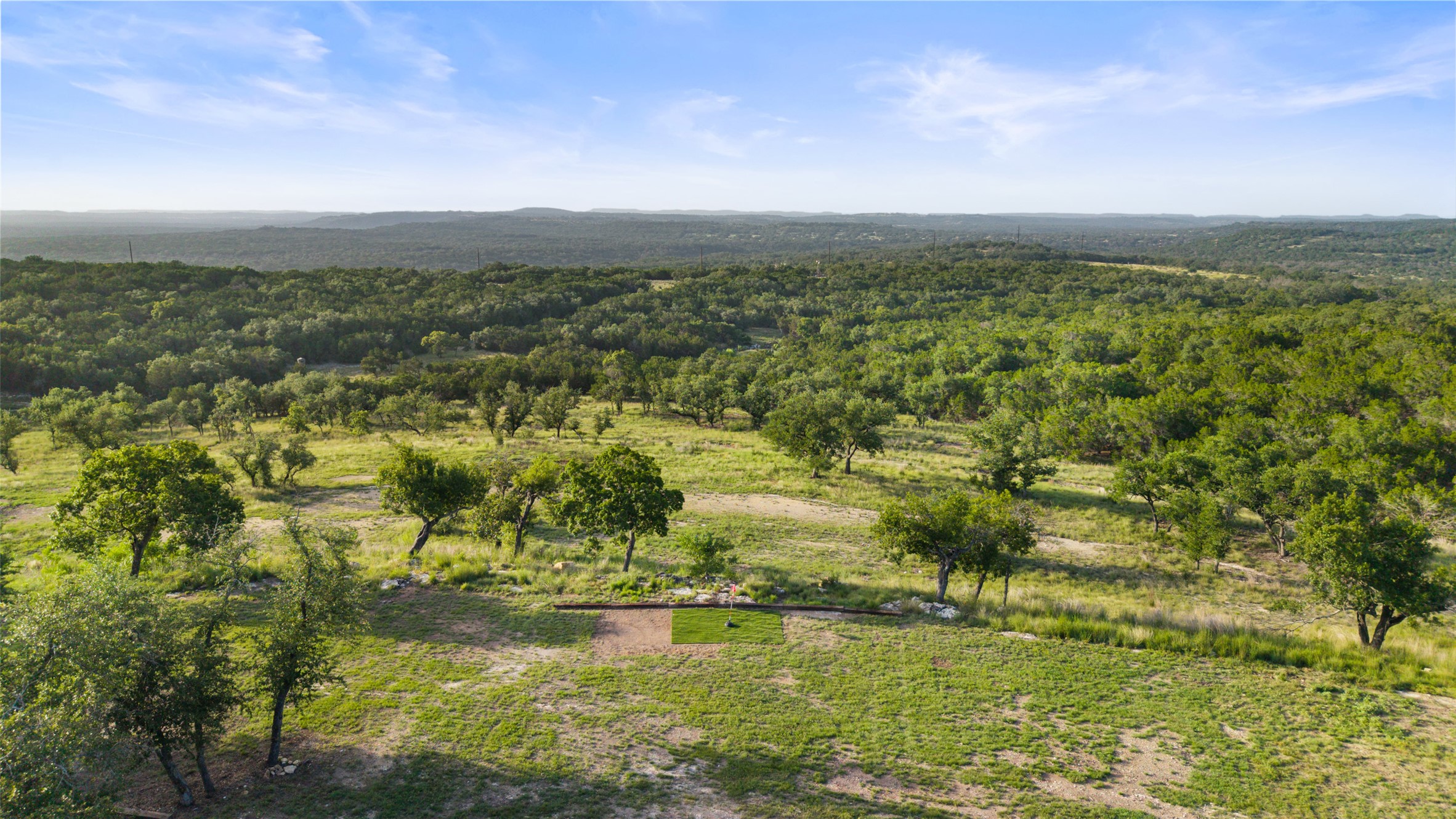 830 Ulrich Road Johnson City, TX 78636 - Photo 12 of 40 Vast, open terrain with verdant trees under an expansive blue sky.