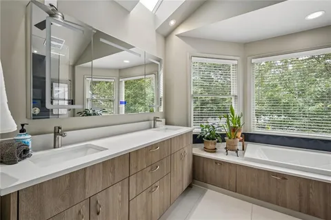a spacious bathroom with a double vanity sink large mirror and a large window