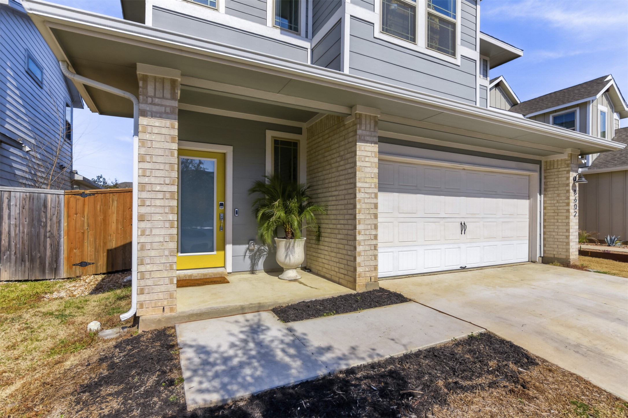 Doorway to property with brick siding, driveway, a porch, and a garage