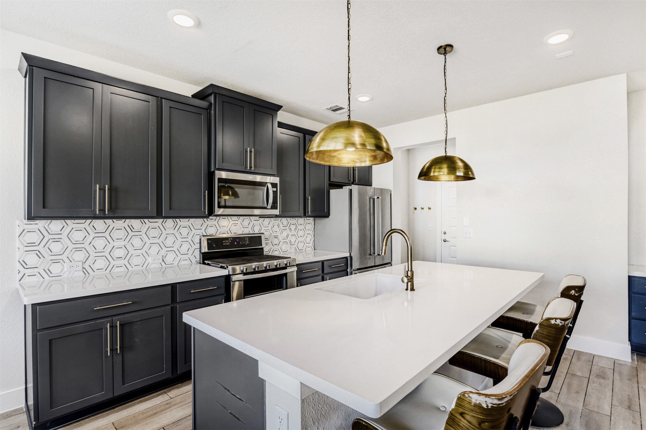 8602 Cottage Rose Drive Austin, TX 78744 - Photo 12 of 17 Kitchen featuring a kitchen breakfast bar, a kitchen island with sink, light wood-style floors, stainless steel appliances, and light stone countertops
