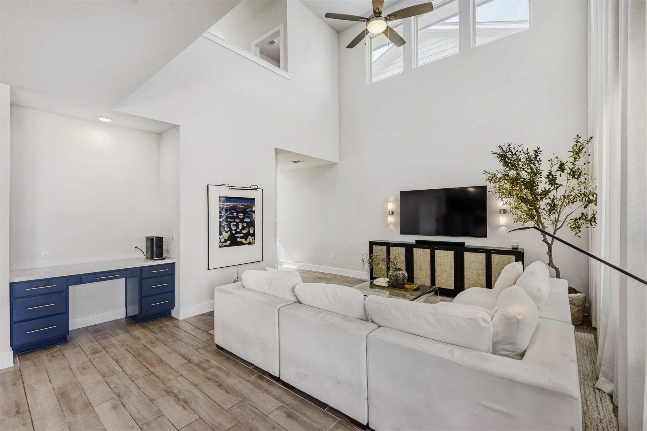 8602 Cottage Rose Drive Austin, TX 78744 - Photo 8 of 17 Living room featuring a ceiling fan, light wood-style flooring, built in desk, and a high ceiling