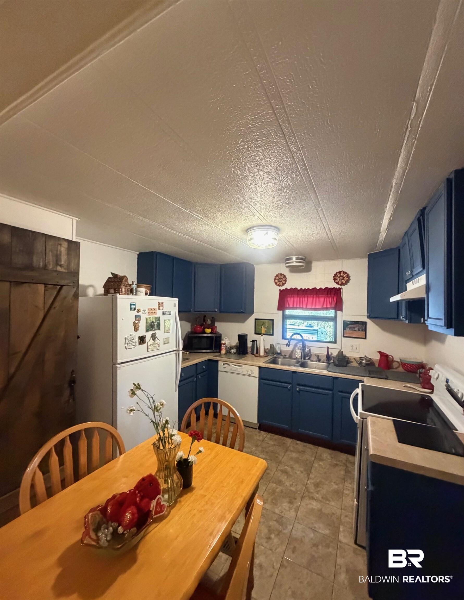 1430 Ridgewood Drive Lillian, AL 36549 - Photo 7 of 34 Kitchen with blue cabinets, white appliances, a textured ceiling, and light countertops