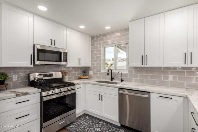 a kitchen with granite countertop white cabinets stainless steel appliances and a sink