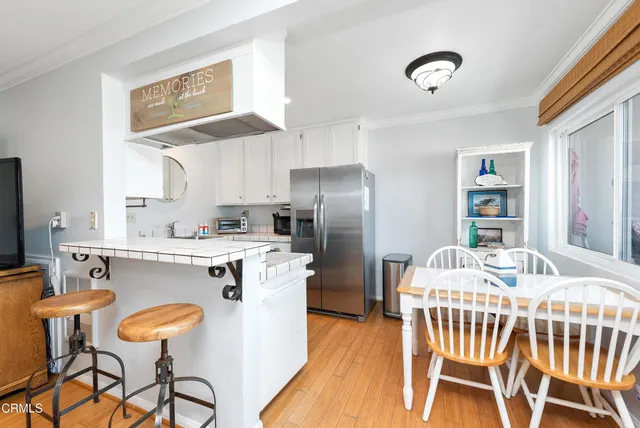 a kitchen with stainless steel appliances granite countertop a dining table chairs and a refrigerator
