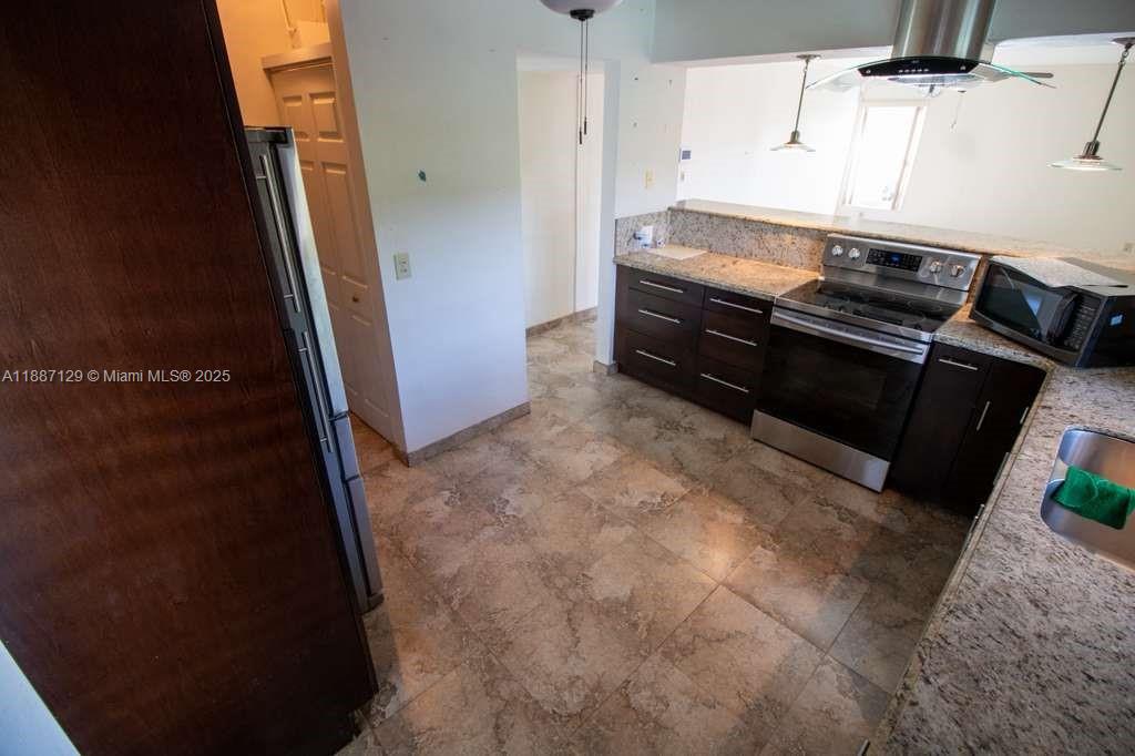 9041 Southwest 88th Street, Unit 9041 Miami, FL 33173 - Photo 30 of 34 a kitchen with granite countertop a stove and a refrigerator