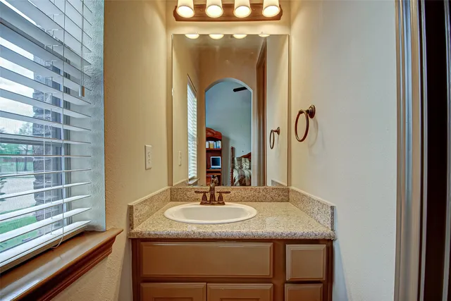 a bathroom with a granite countertop sink a mirror and shower