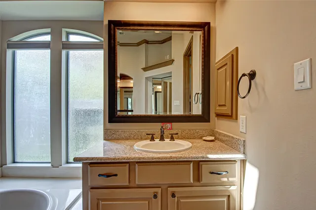 a bathroom with a granite countertop sink a mirror and a shower