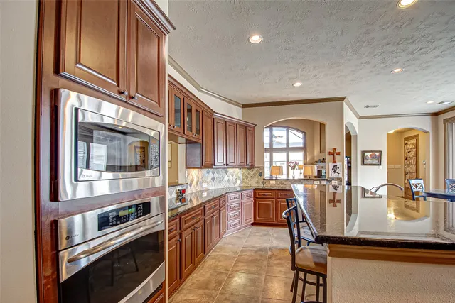 a very nice looking kitchen with granite countertop a stove and cabinets