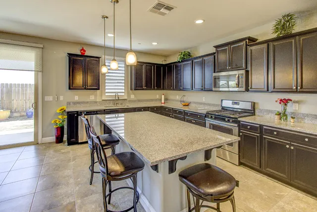 a kitchen with stainless steel appliances granite countertop a sink wooden cabinets a stove and a granite counter tops
