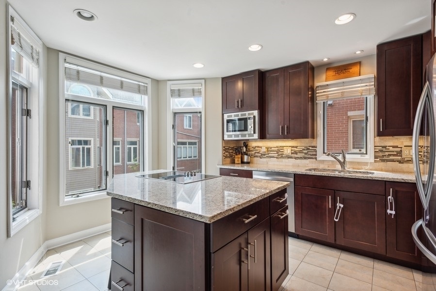 1231 West Fletcher Street, Unit A Chicago, IL 60657 - Photo 5 of 20 a kitchen with stainless steel appliances granite countertop a sink and a stove