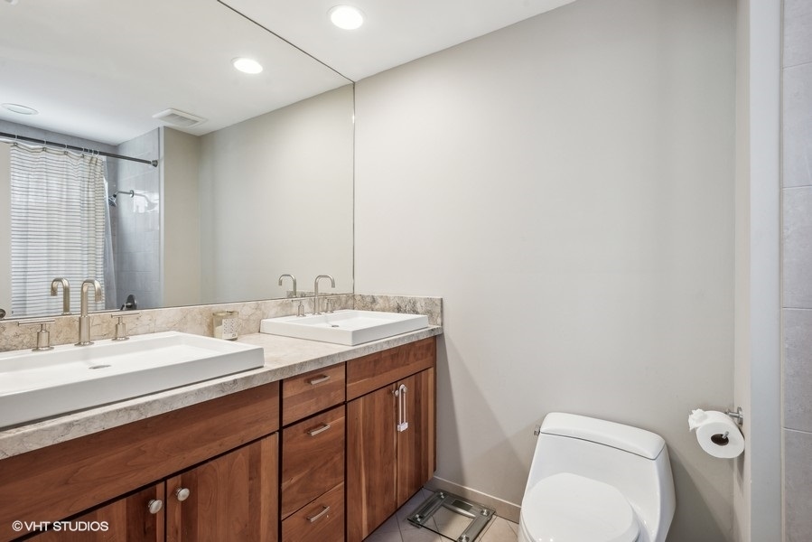 1231 West Fletcher Street, Unit A Chicago, IL 60657 - Photo 9 of 20 a bathroom with a granite countertop sink a toilet and a mirror