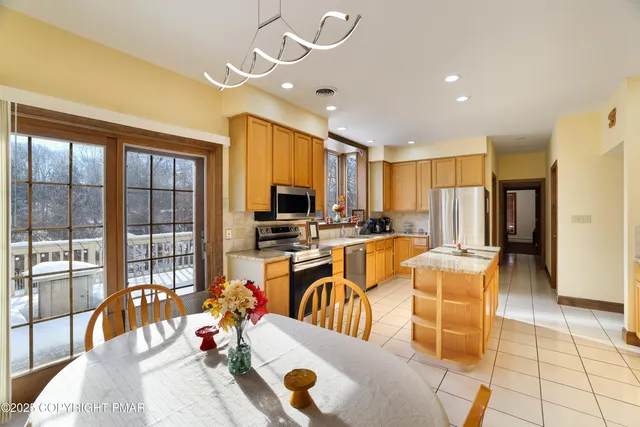 a kitchen with stainless steel appliances granite countertop a stove top oven a sink dishwasher a dining table and chairs with wooden floor