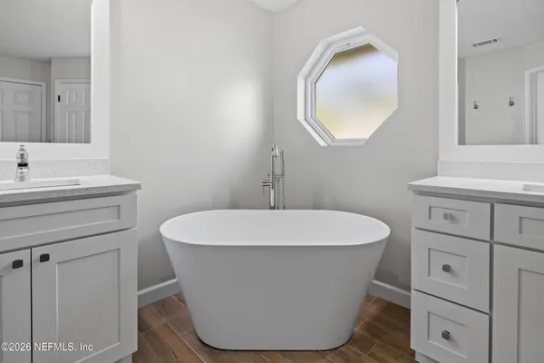 a bathroom with a double vanity sink mirror and bathtub