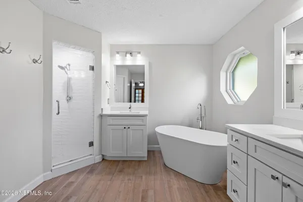 a spacious bathroom with a double vanity sink mirror and bathtub