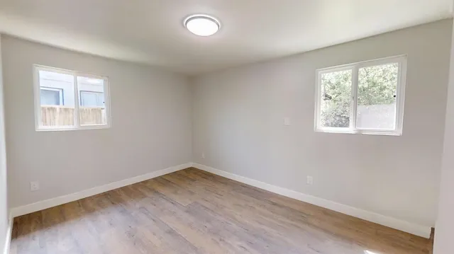an empty room with wooden floor and windows