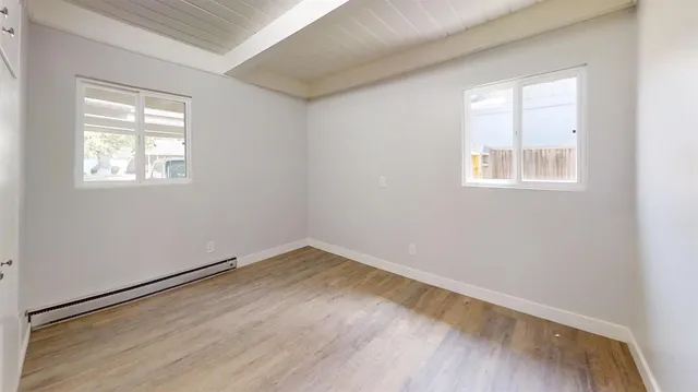 an empty room with wooden floor and windows