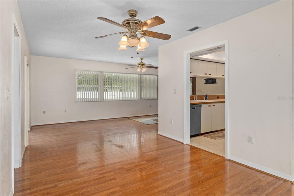 3217 Abeline Road Spring Hill, FL 34608 - Photo 13 of 48 an empty room with wooden floor chandelier fan and windows
