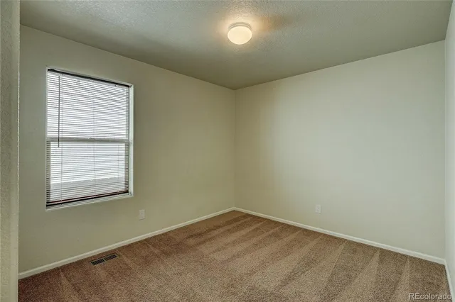 a view of an empty room with window and closet area