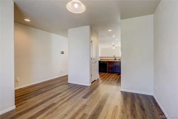 a view of a room with wooden floor and a kitchen