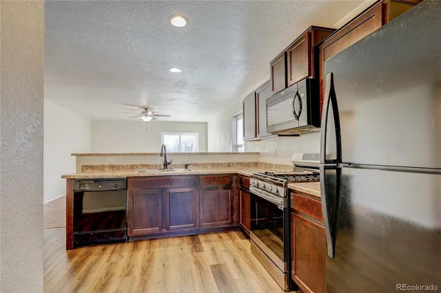 a kitchen with stainless steel appliances granite countertop a stove a sink and a refrigerator
