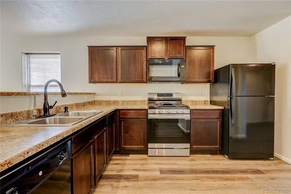 a kitchen with stainless steel appliances granite countertop a refrigerator stove and sink