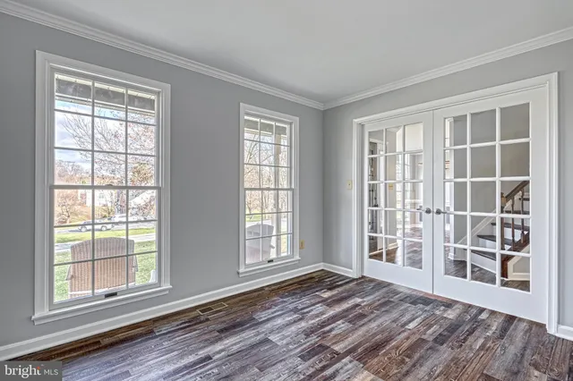 a view of an empty room with a window and wooden floor