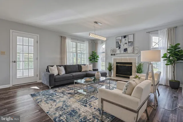 an empty room with wooden floor a chandelier fan and windows