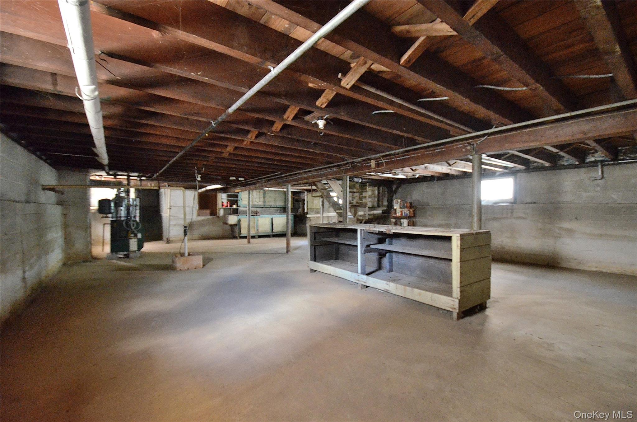 2586 Riverside Drive Wantagh, NY 11793 - Photo 23 of 28 Spacious basement featuring exposed wood ceiling joists and support beams, concrete flooring, concrete block walls, and a visible utility area