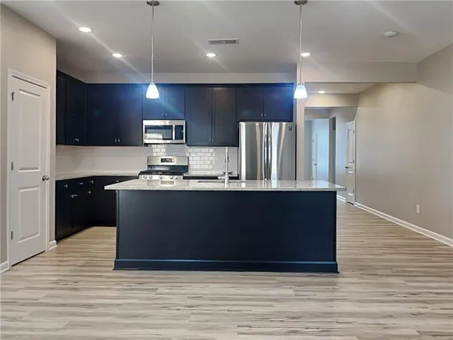 a kitchen with kitchen island stainless steel appliances a sink refrigerator and cabinets