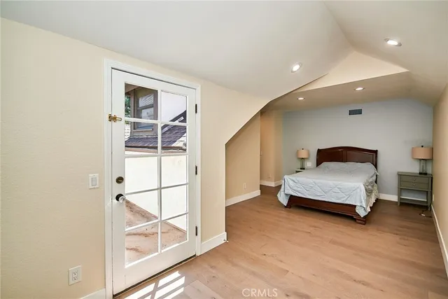 a spacious bedroom with a bed and wooden floor