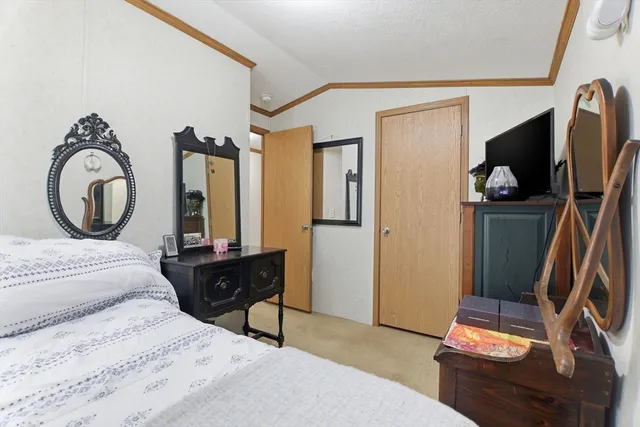 a bedroom with a bed and a flat tv screen on dresser