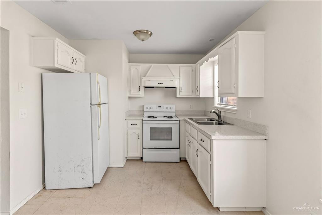 4601 South 24th Street, Unit 7 McAllen, TX 78503 - Photo 4 of 7 Kitchen with white appliances, exhaust hood, white cabinets, and light countertops