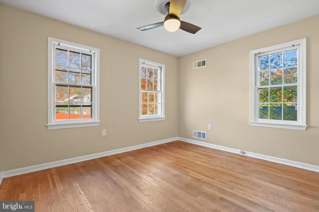a view of an empty room with a window and wooden floor