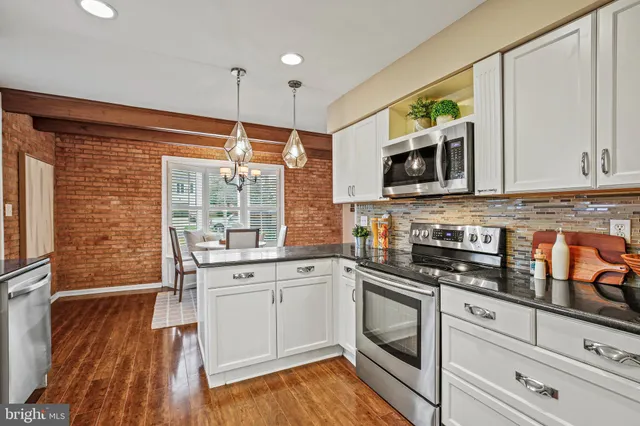 a kitchen with stainless steel appliances granite countertop a stove a sink and white cabinets