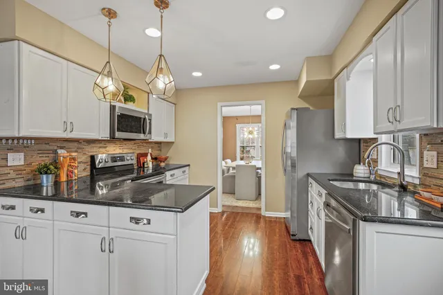 a kitchen with granite countertop a sink a counter space appliances and cabinets