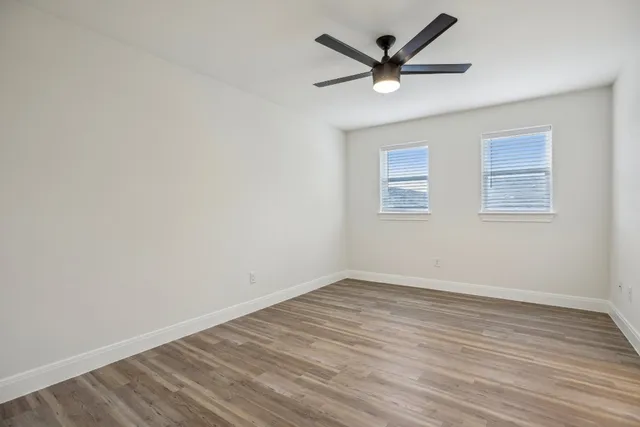 an empty room with wooden floor and a ceiling fan