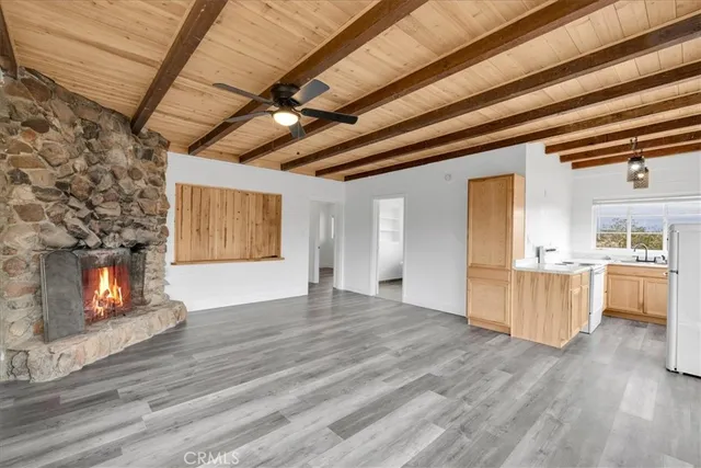 a view of an empty room with a fireplace and wooden floor