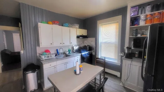 a kitchen with a refrigerator a stove a sink dishwasher and a dining table with wooden floor