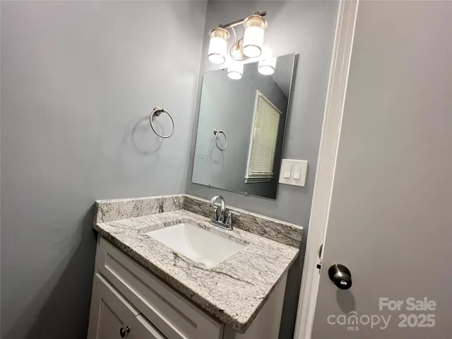 a bathroom with a granite countertop sink a light fixture and a mirror