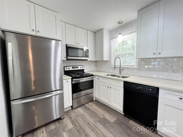 a kitchen with stainless steel appliances white cabinets a sink and a refrigerator