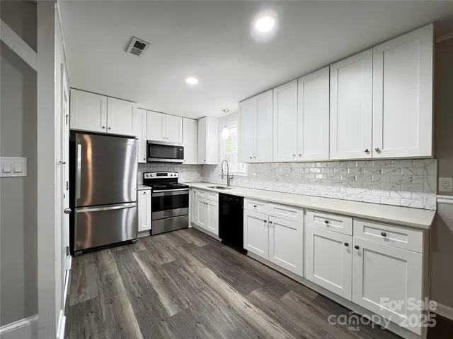 a kitchen with granite countertop white cabinets and stainless steel appliances