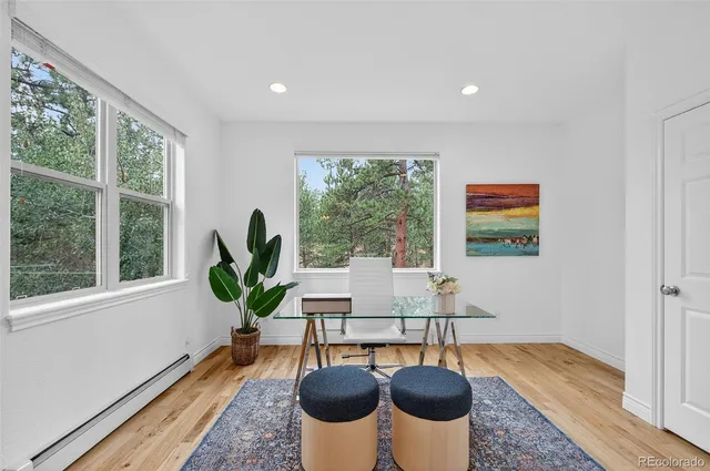 a living room with furniture a large window and wooden floor
